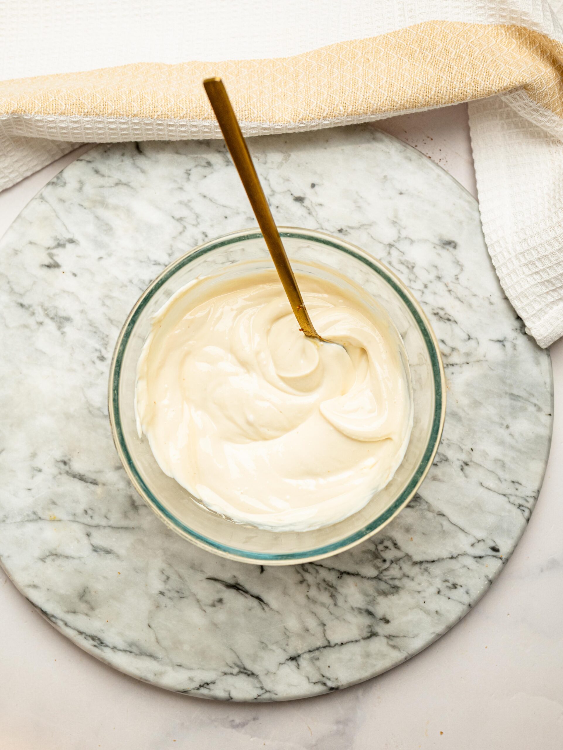 Cream cheese and honey mixture stirred until smooth in a glass mixing bowl for the cheesecake filling.