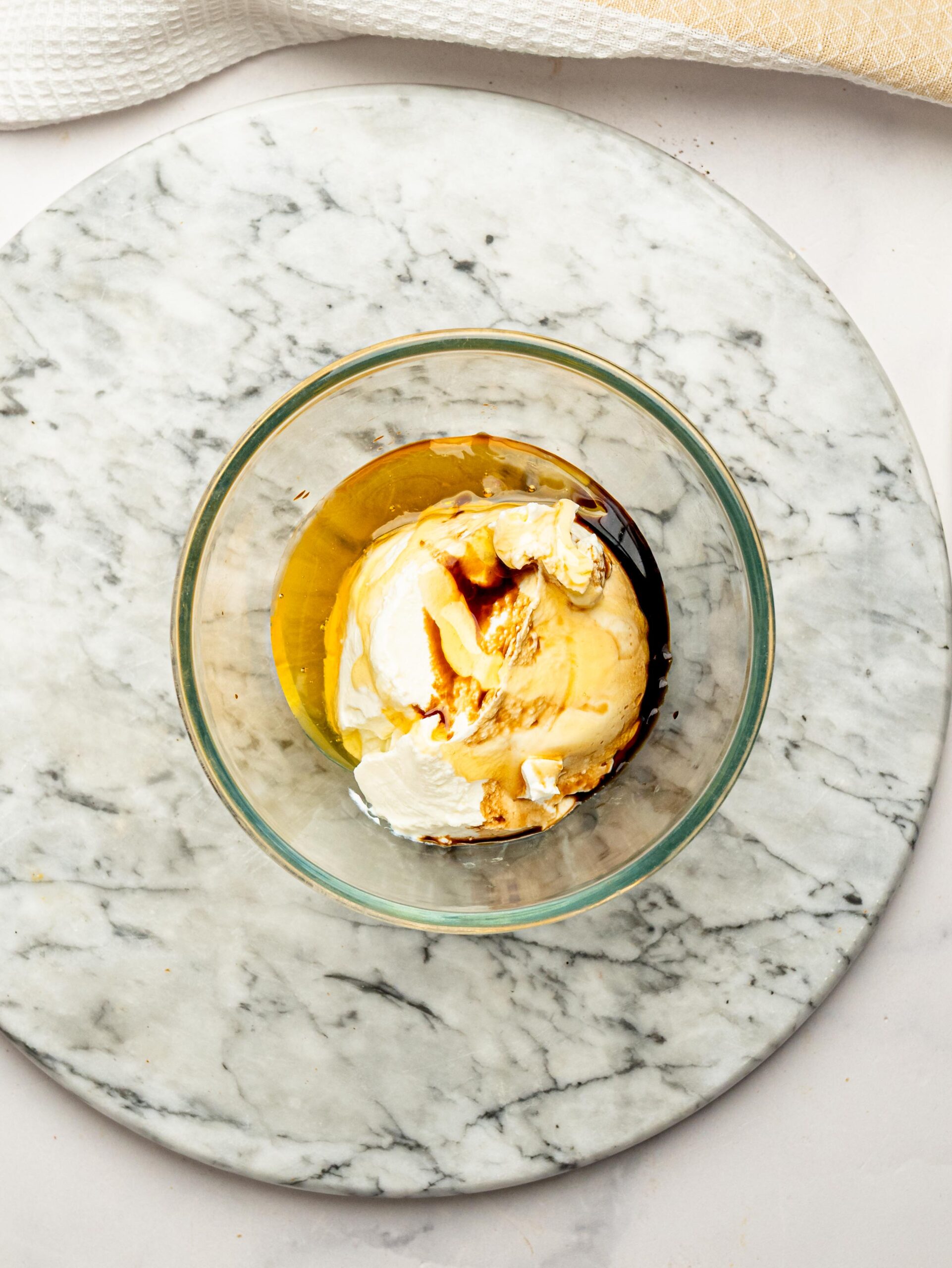 Cream cheese, honey, and vanilla extract in a glass bowl before mixing into the cheesecake filling.