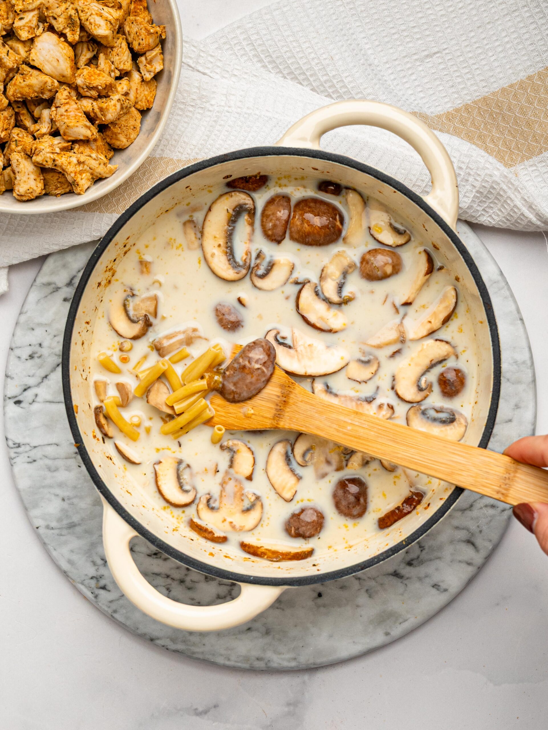 Macaroni, mushrooms, milk, and chicken stock cooking together in one pot.
