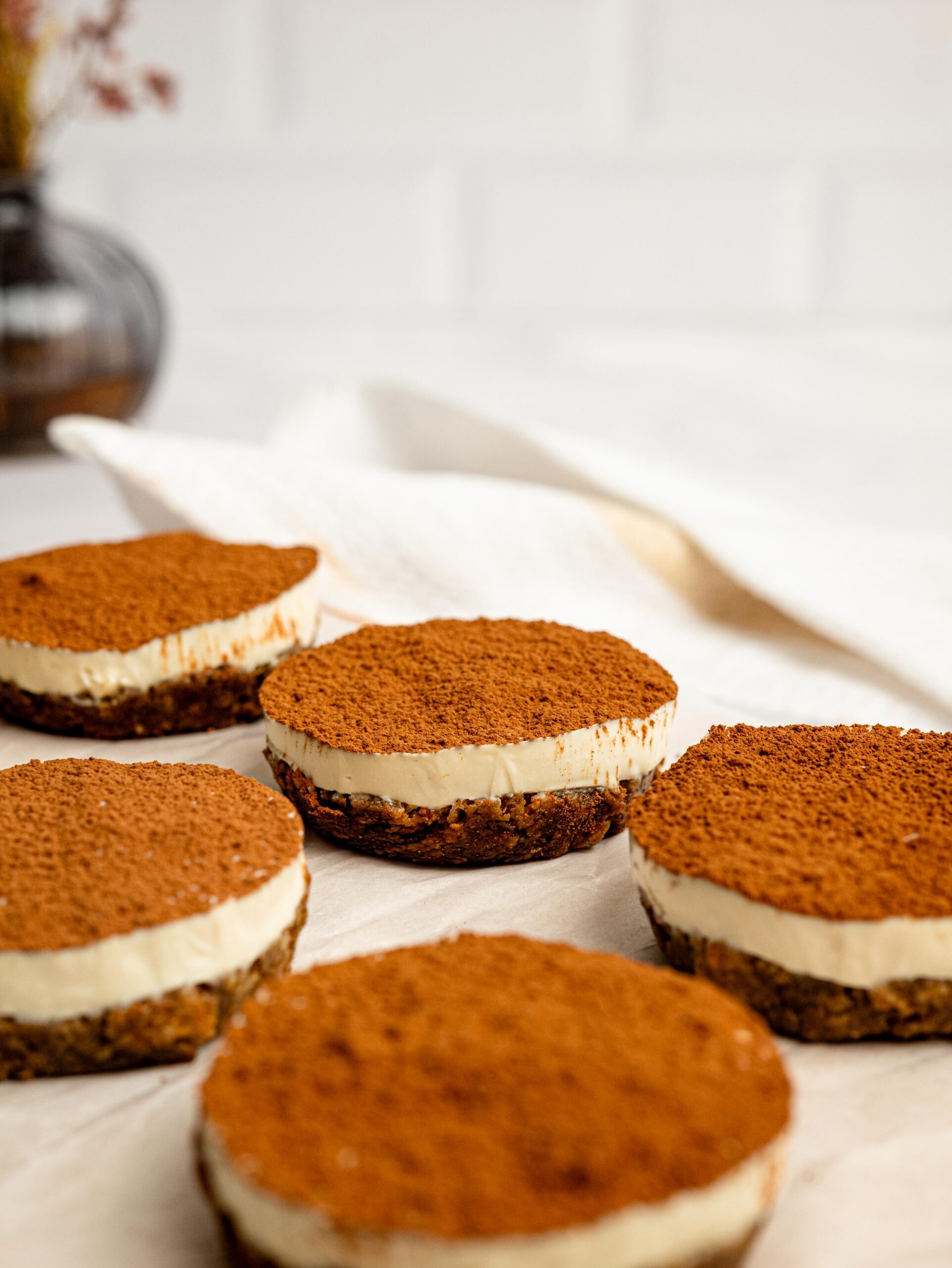 Mini Tiramisu Cheesecake Weetbix Cups arranged on a wooden board with a generous dusting of cocoa powder.