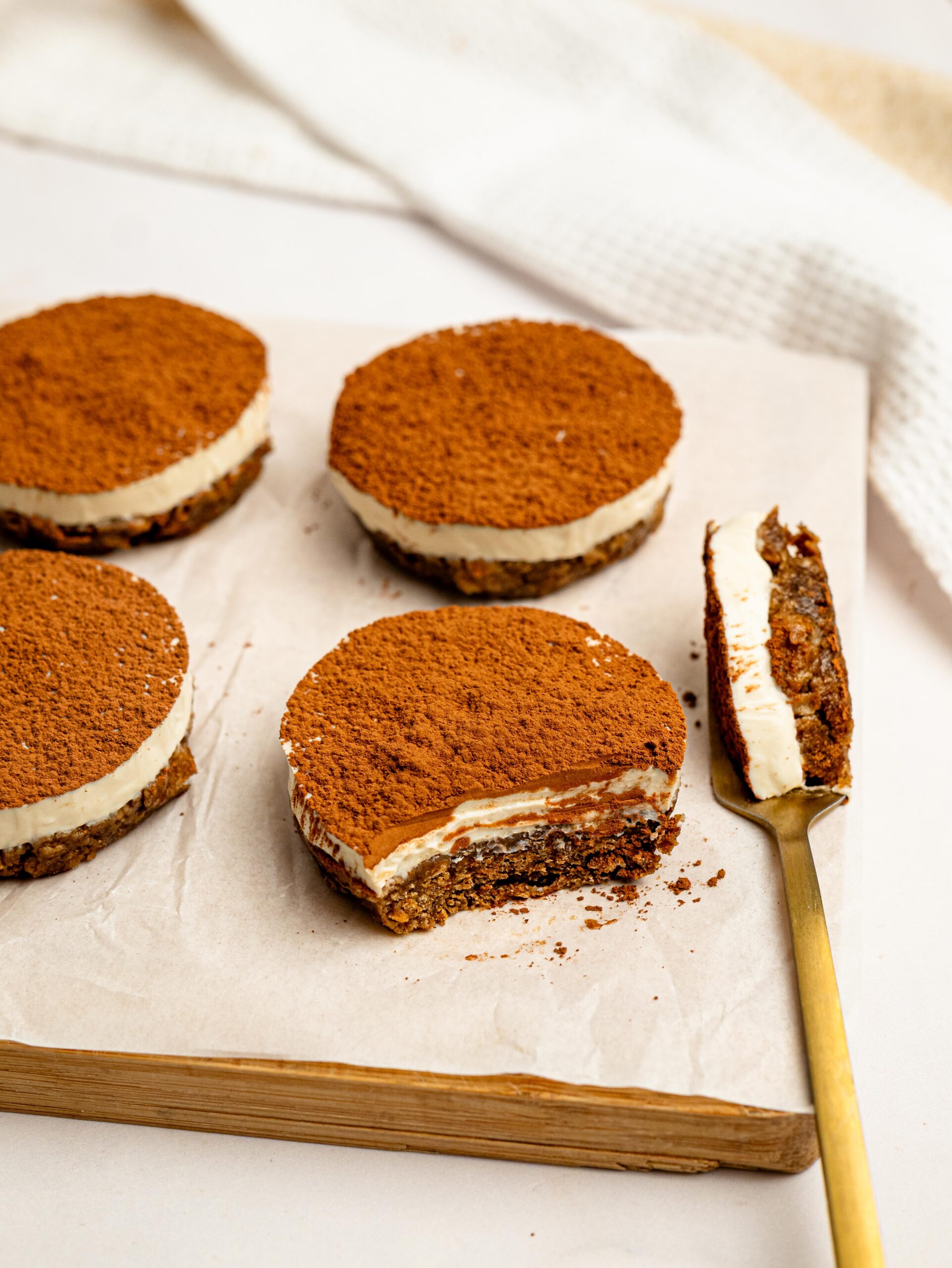 No-bake Mini Tiramisu Cheesecake Weetbix Cups with one bite taken out, showing the creamy cheesecake layer and coffee-flavored base.