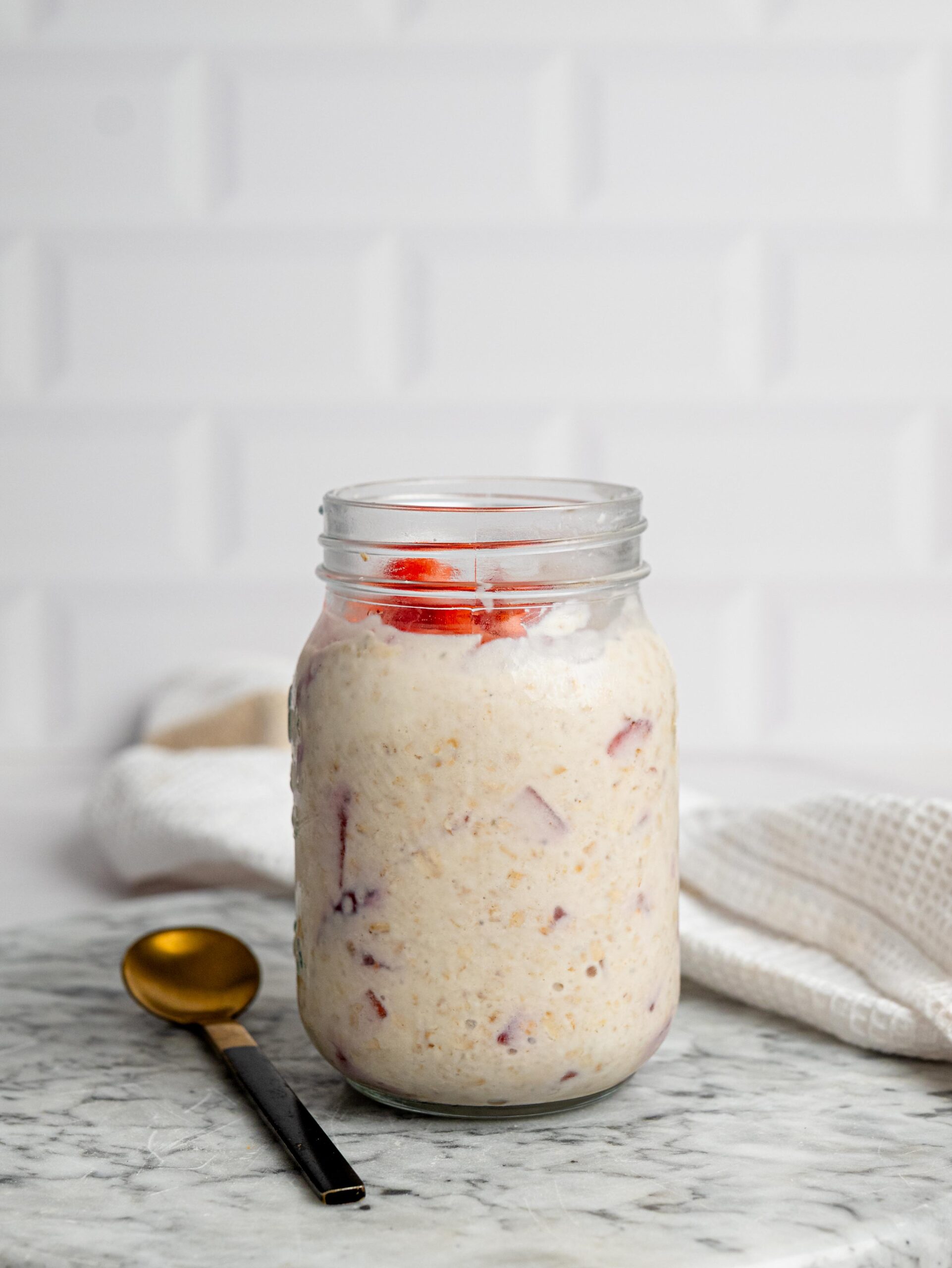 vanilla overnight oats with strawberries Jar of vanilla overnight oats with protein powder topped with fresh strawberries.