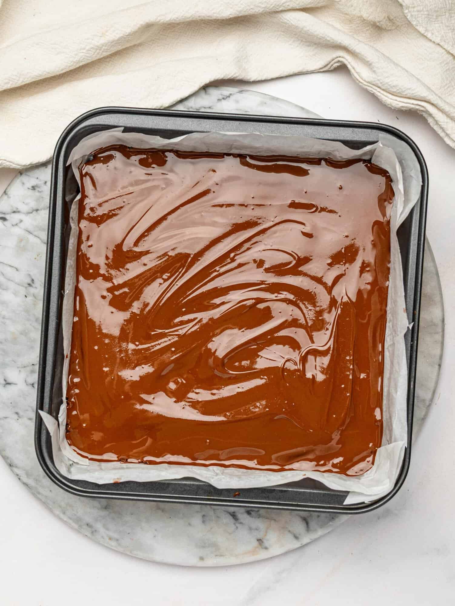 Homemade no-bake chocolate protein bars topped with melted dark chocolate before chilling.
