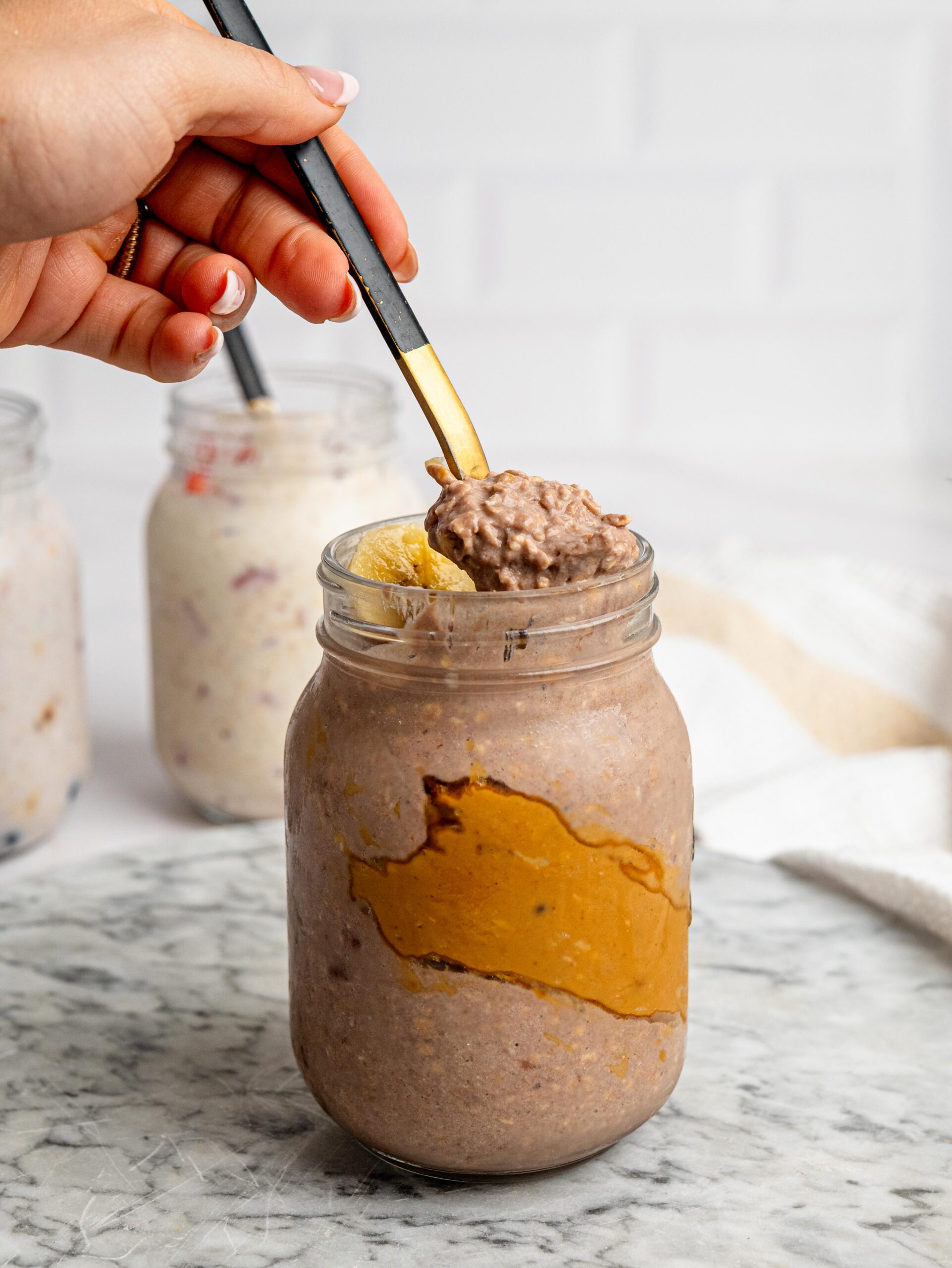 chocolate protein overnight oats Spoonful of chocolate protein overnight oats topped with sliced banana.