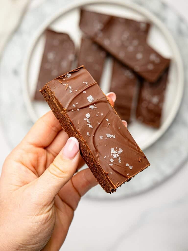 Close-up of a chocolate protein snack bar with a glossy chocolate coating and flaky sea salt.