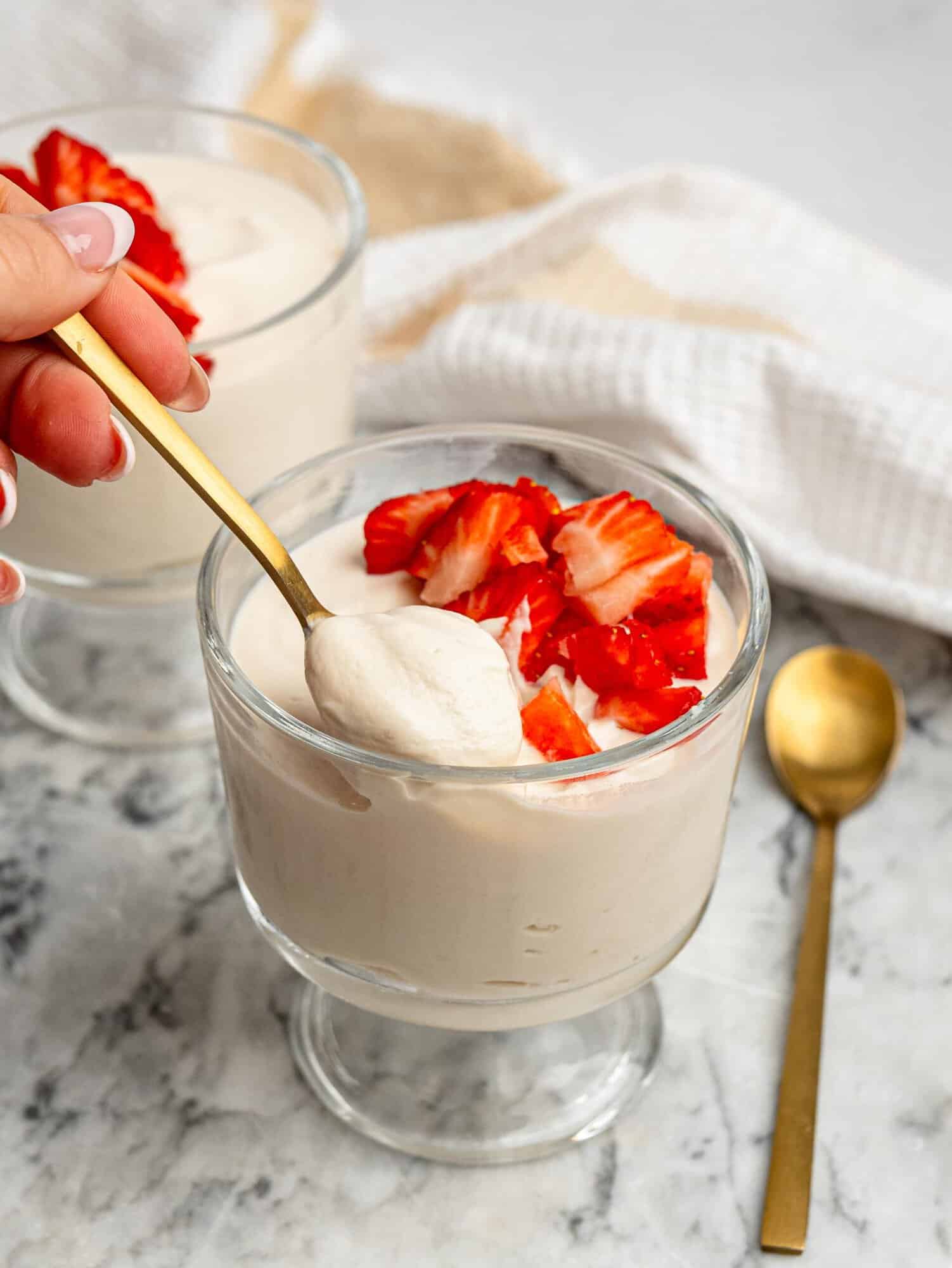 Spoon serving creamy protein pudding with fresh strawberries.