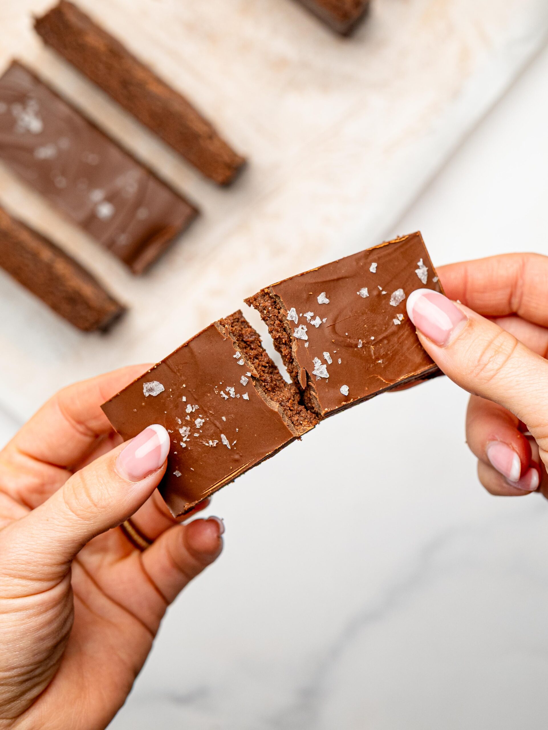 Chocolate protein snack bar being broken in half to reveal its soft fudgy center.