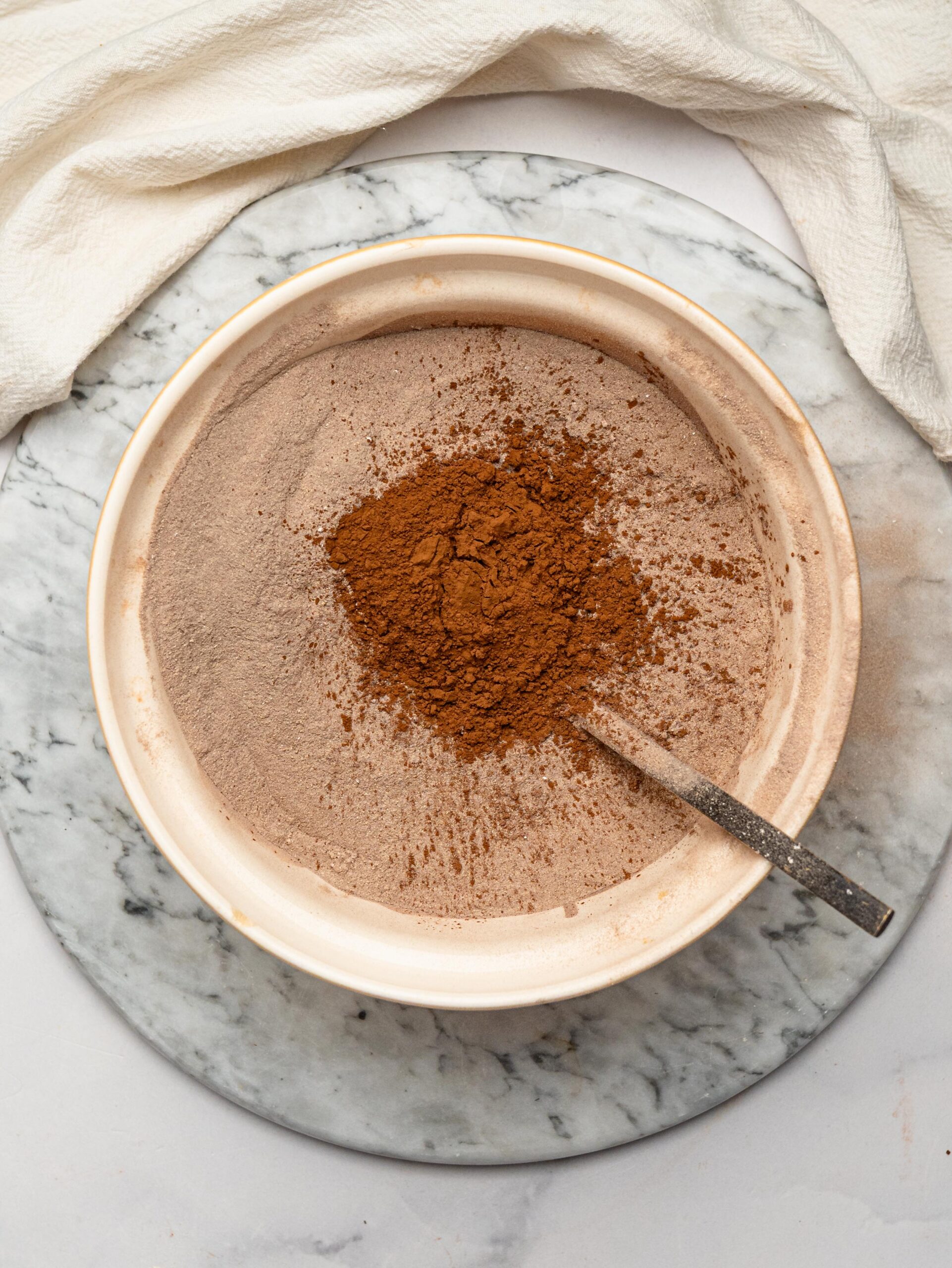 Chocolate protein powder, cocoa powder, and oat flour combined in a mixing bowl for homemade protein bars.
