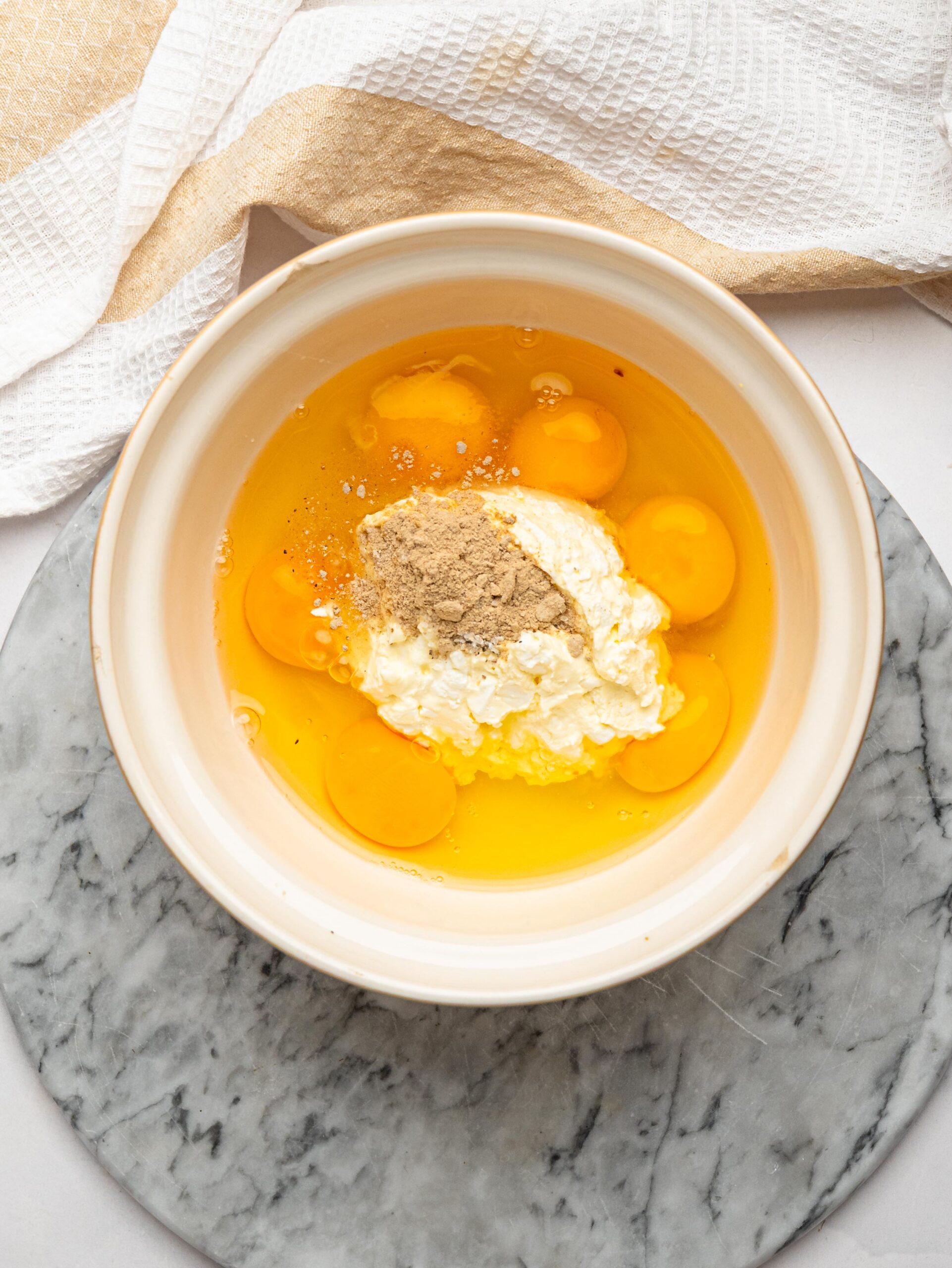 Eggs with cottage cheese, salt and pepper in a bowl before whisking.