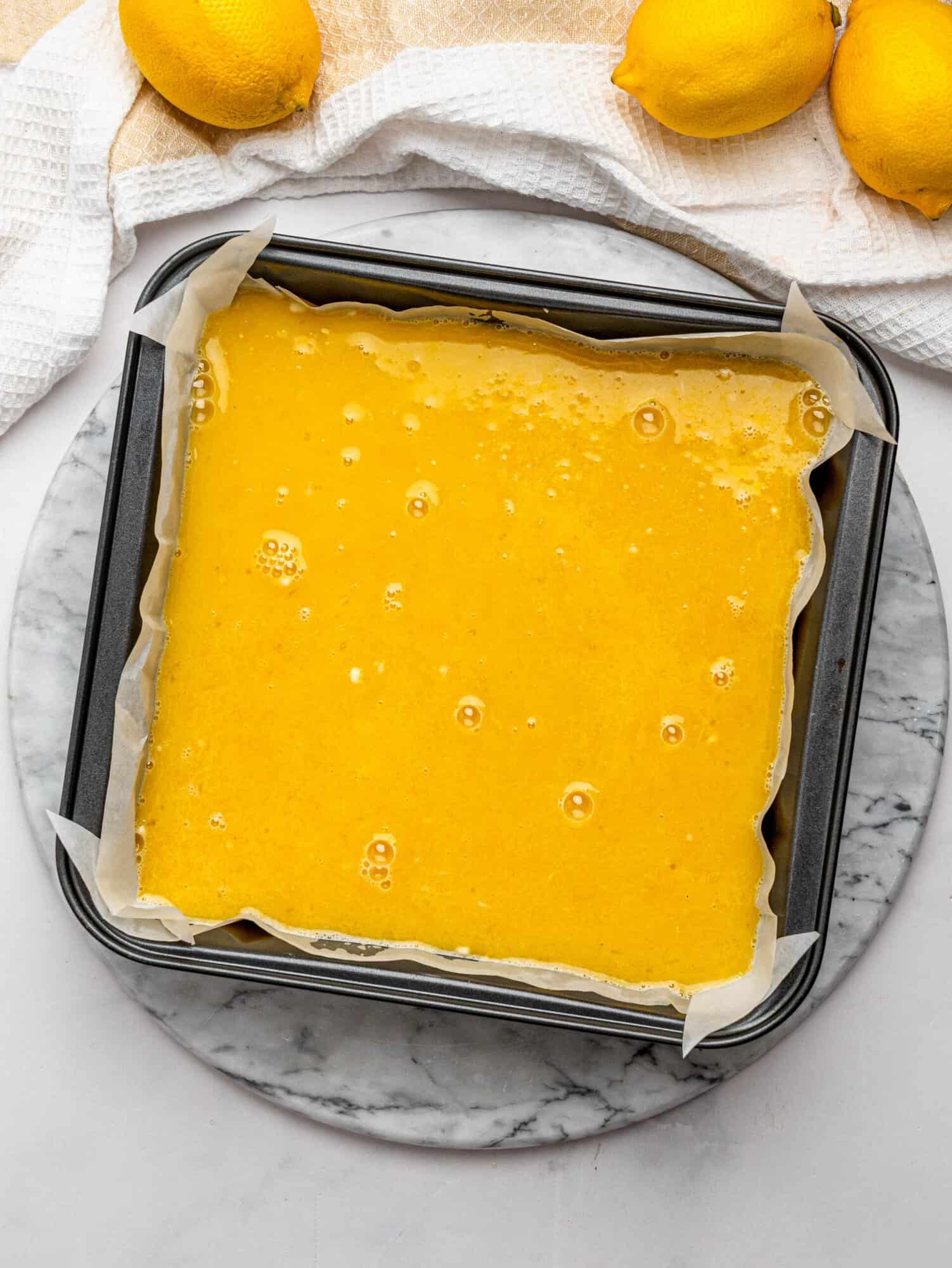 Lemon filling poured over the shortbread crust in a baking pan.