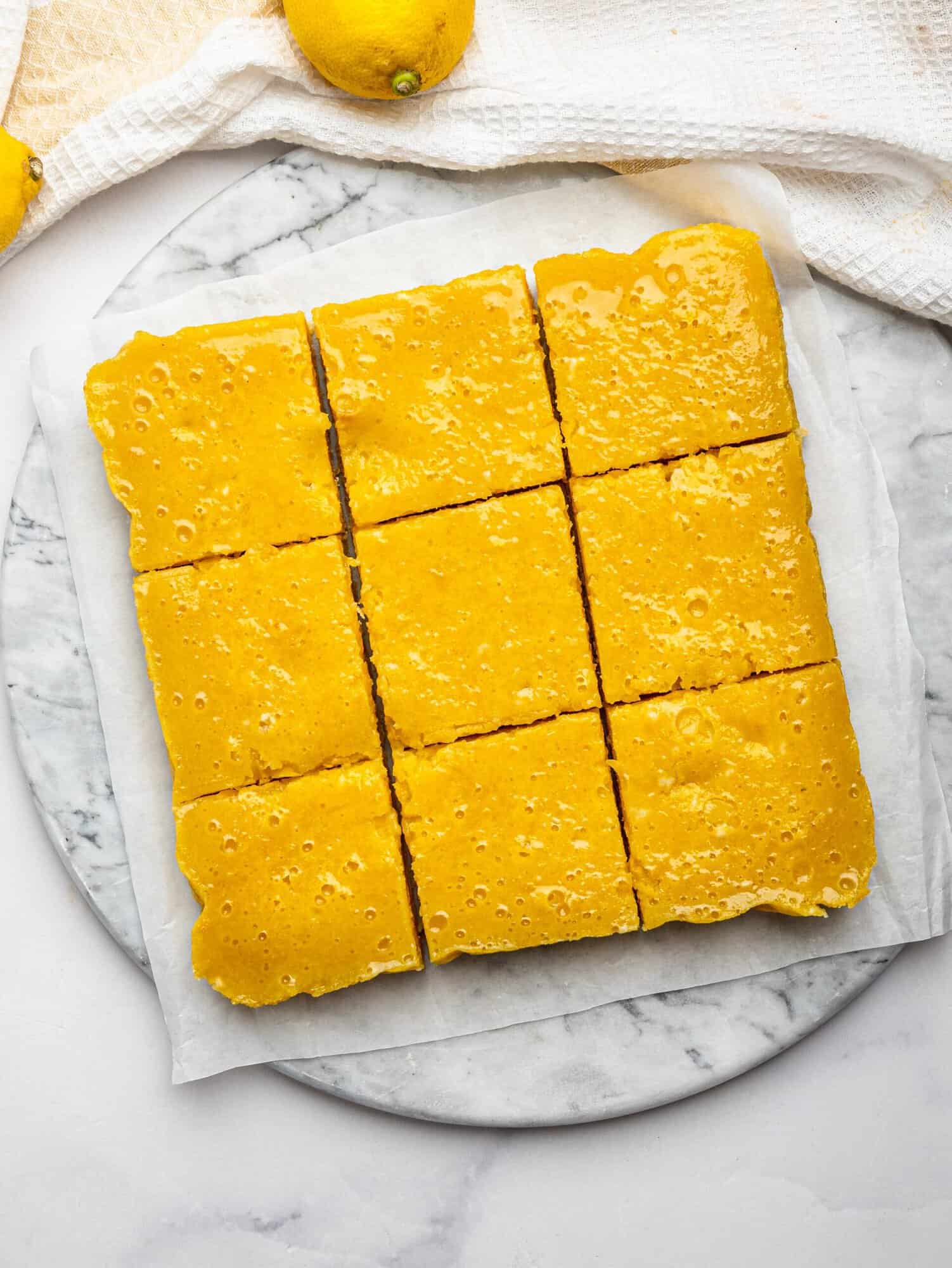 Sliced gluten free lemon bars on parchment paper.