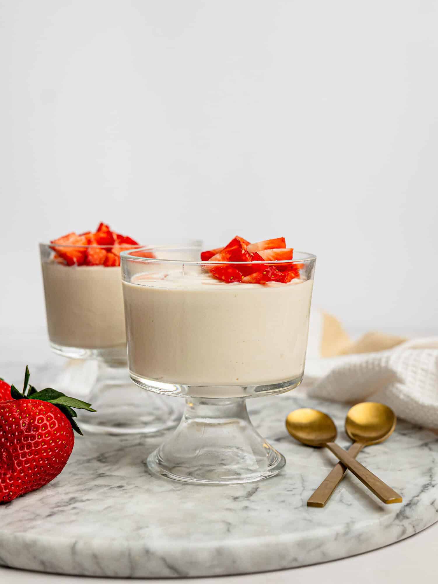 Two servings of creamy protein pudding topped with fresh strawberries.