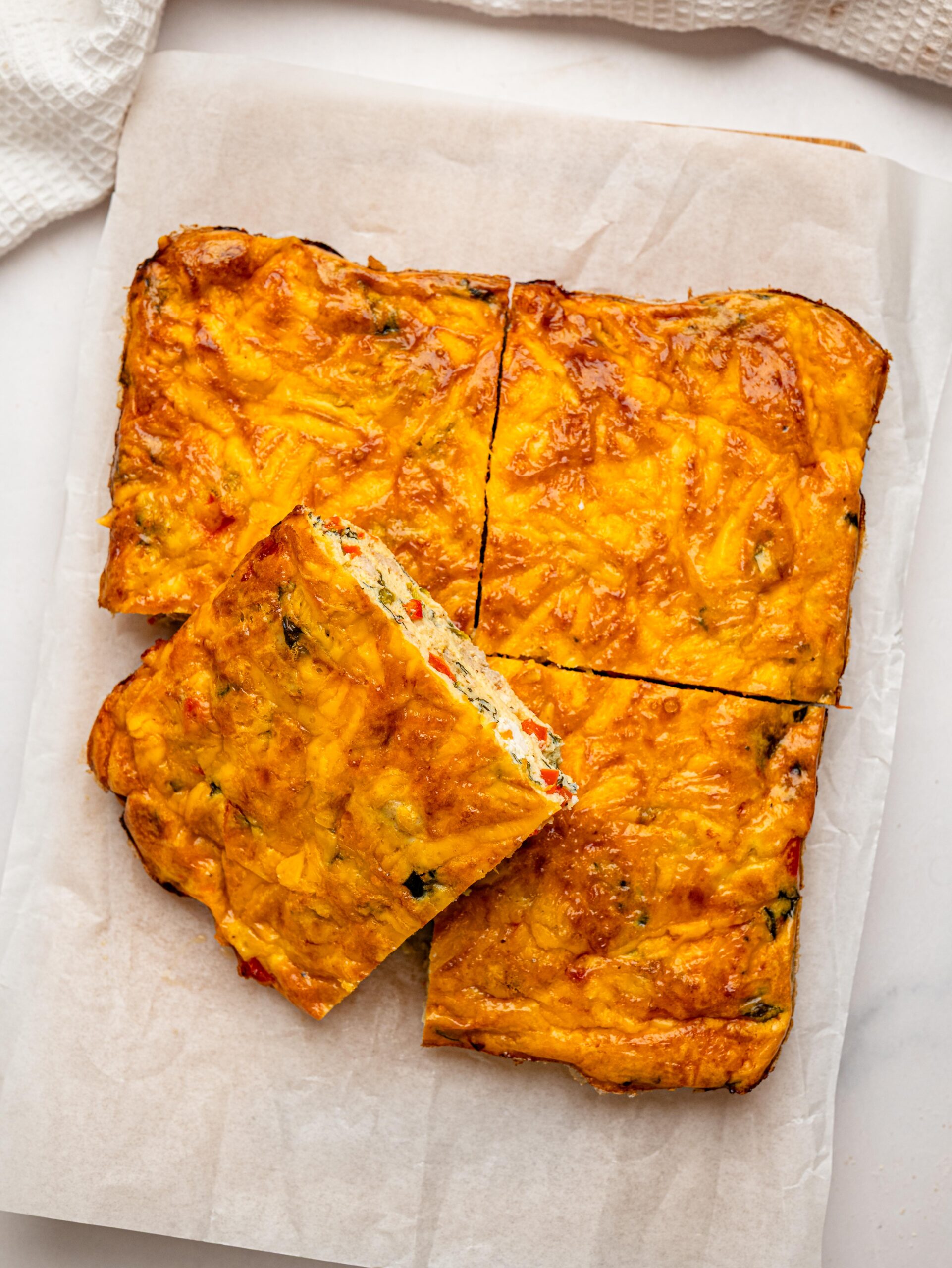 Four squares of baked egg casserole topped with melted cheddar cheese.