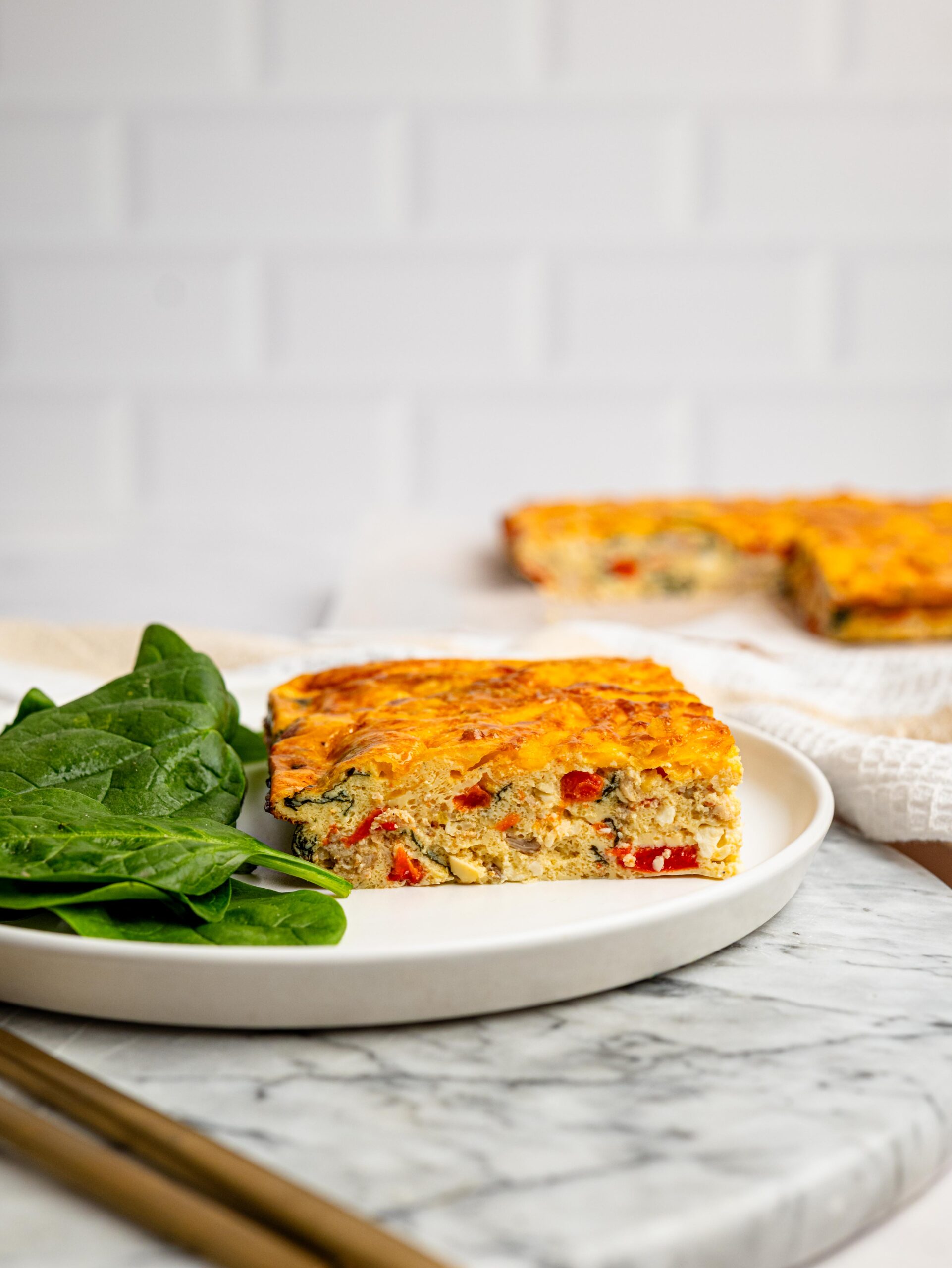 Side view of a thick slice of high protein egg bake with vegetables and sausage.