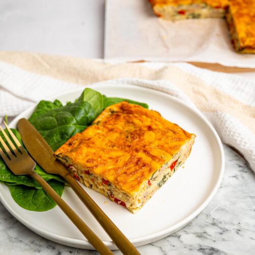 Slice of high protein egg bake with cottage cheese served with spinach.