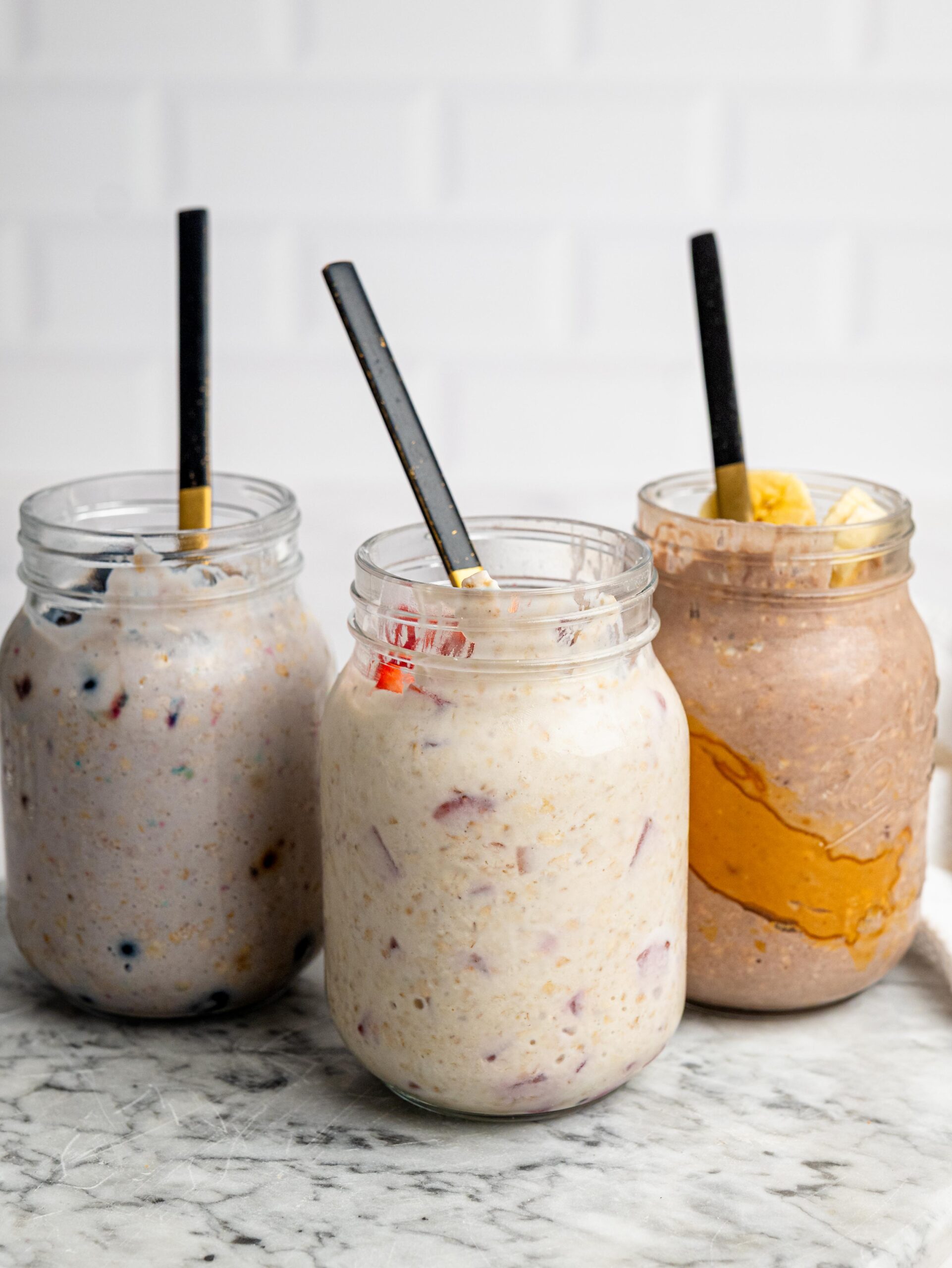 Three jars of overnight oats with protein powder in different flavors.