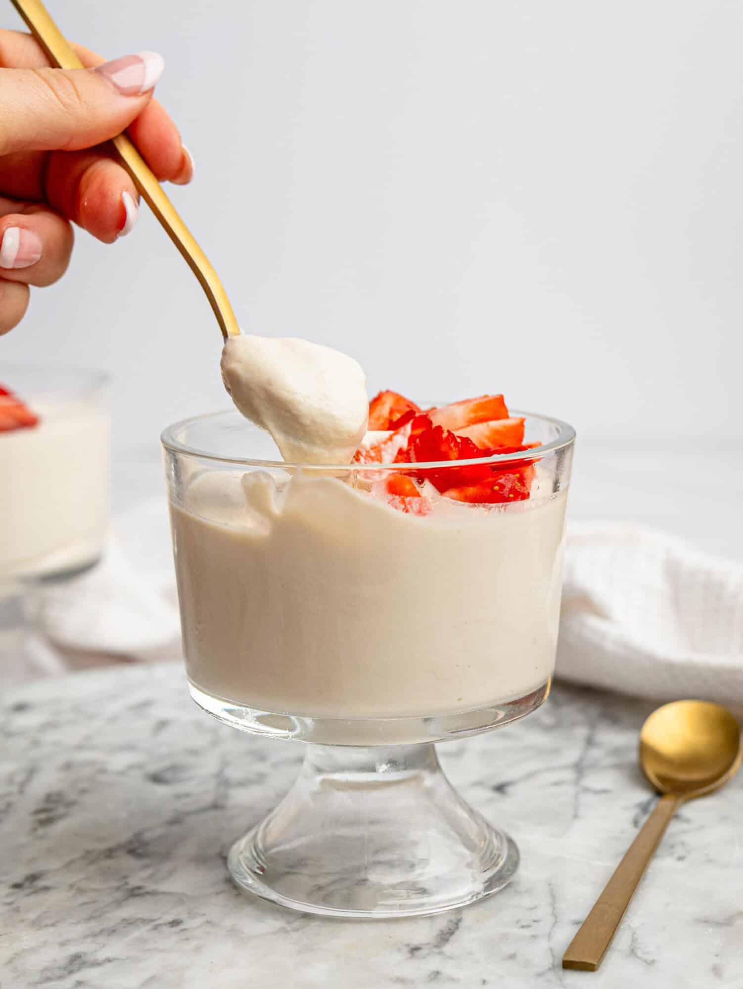 Spoonful of creamy protein powder pudding topped with fresh strawberries.