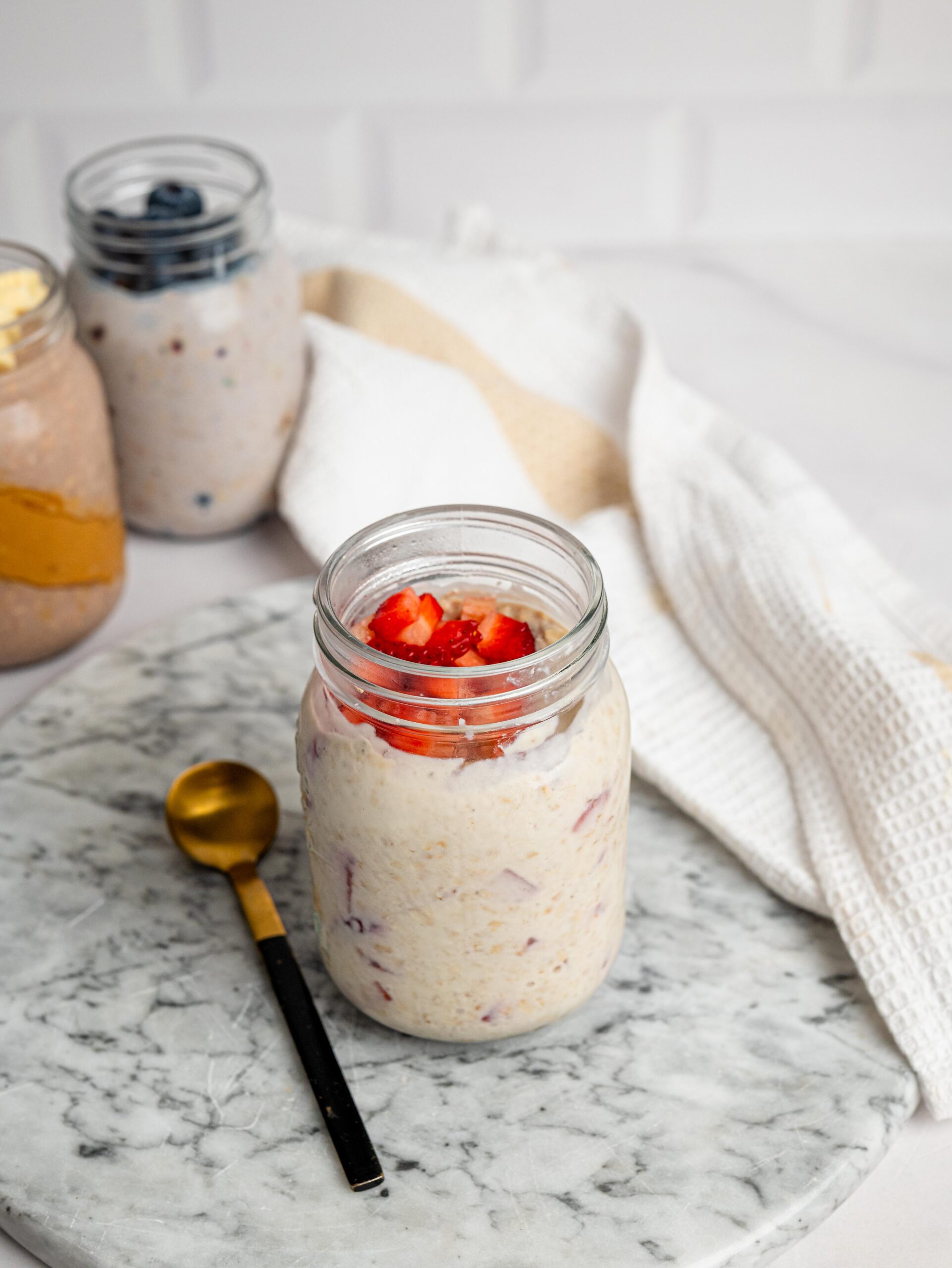strawberry overnight oats Jar of strawberry overnight oats with protein powder topped with fresh strawberries.