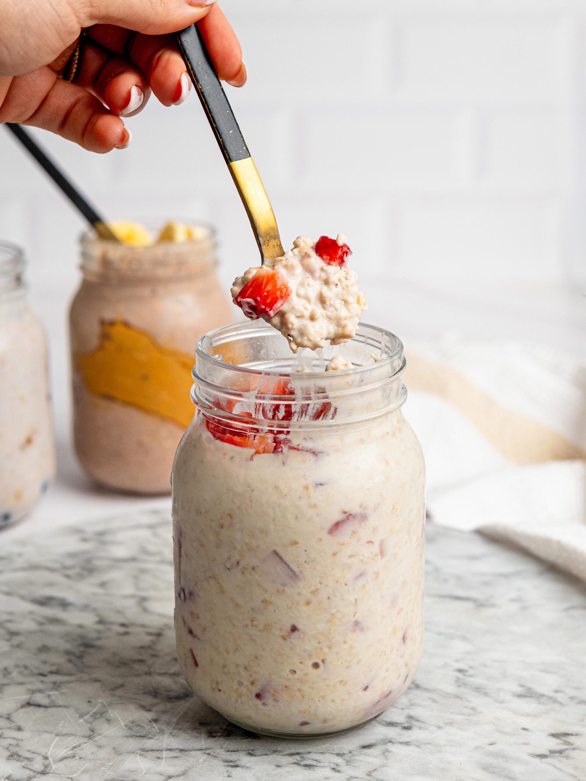 strawberry protein overnight oats Spoonful of strawberry protein overnight oats topped with fresh strawberries.