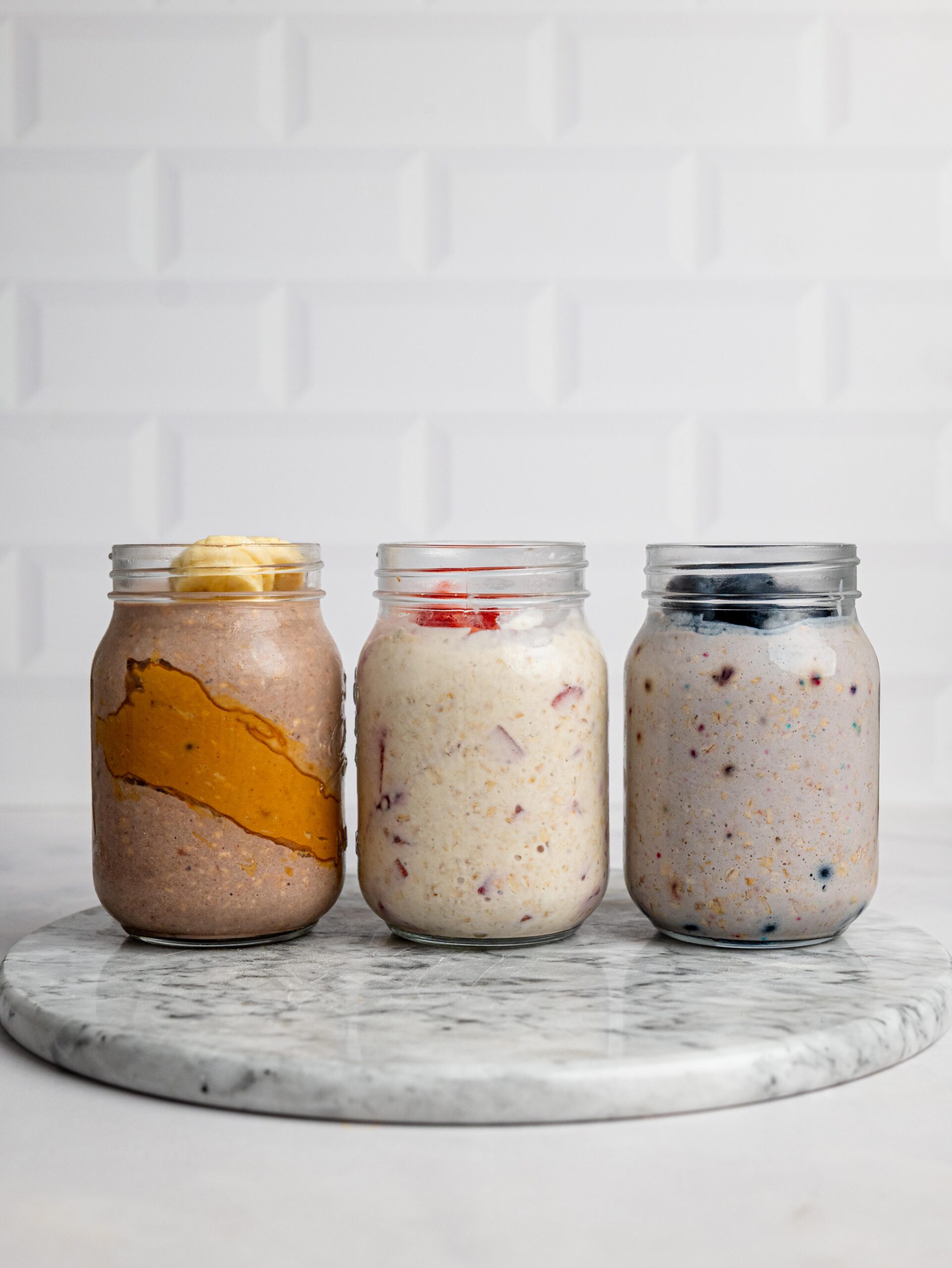 thick and creamy protein overnight oats Three jars of thick and creamy protein overnight oats with different toppings.