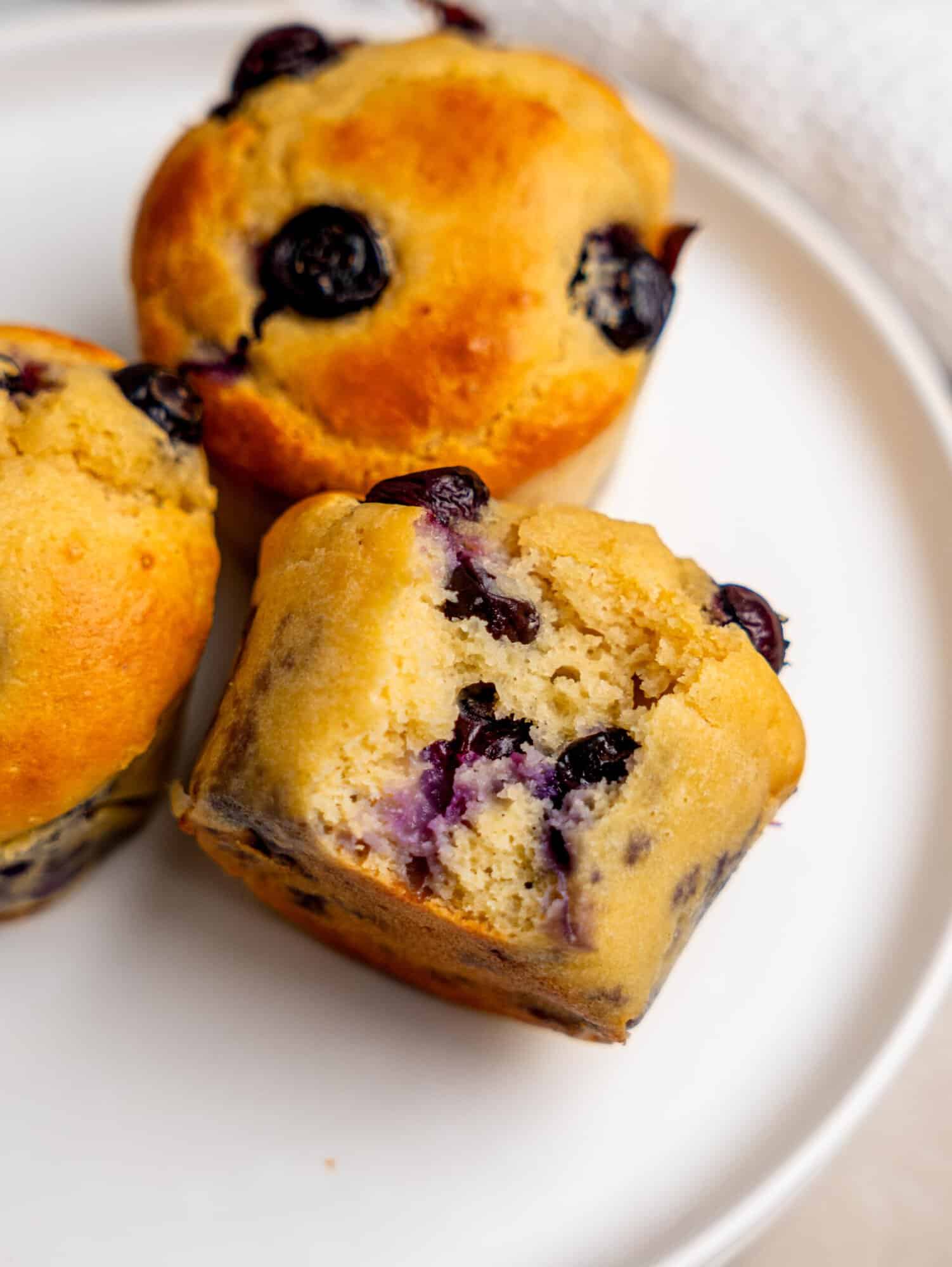 Close-up of soft high protein blueberry muffins with juicy blueberries throughout.