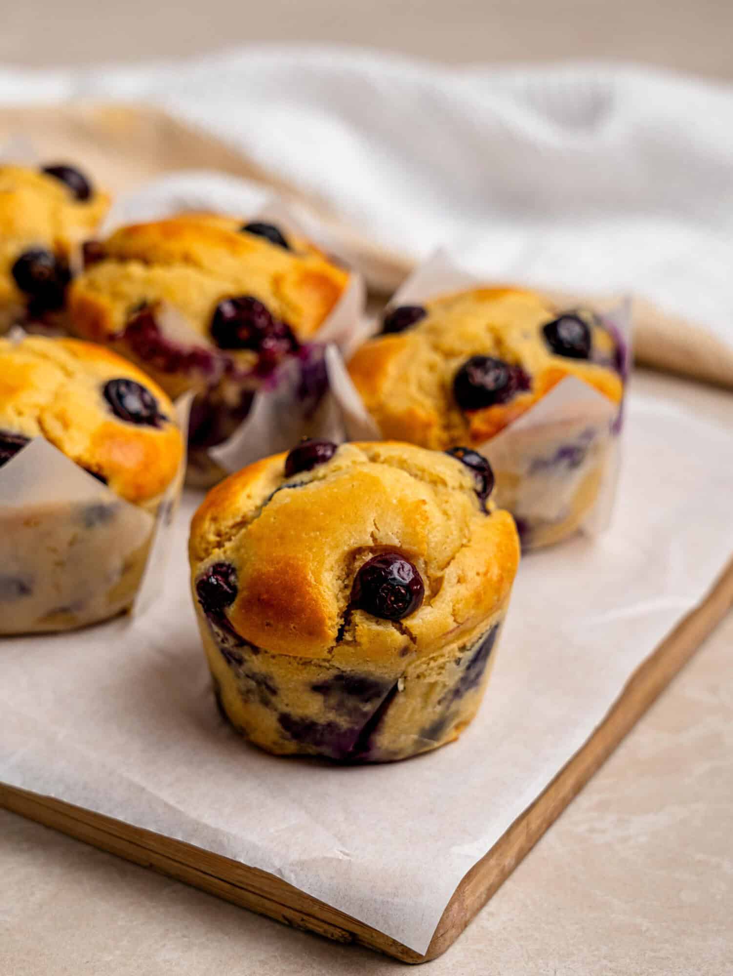 Freshly baked protein blueberry muffins arranged on parchment paper, ready for meal prep.