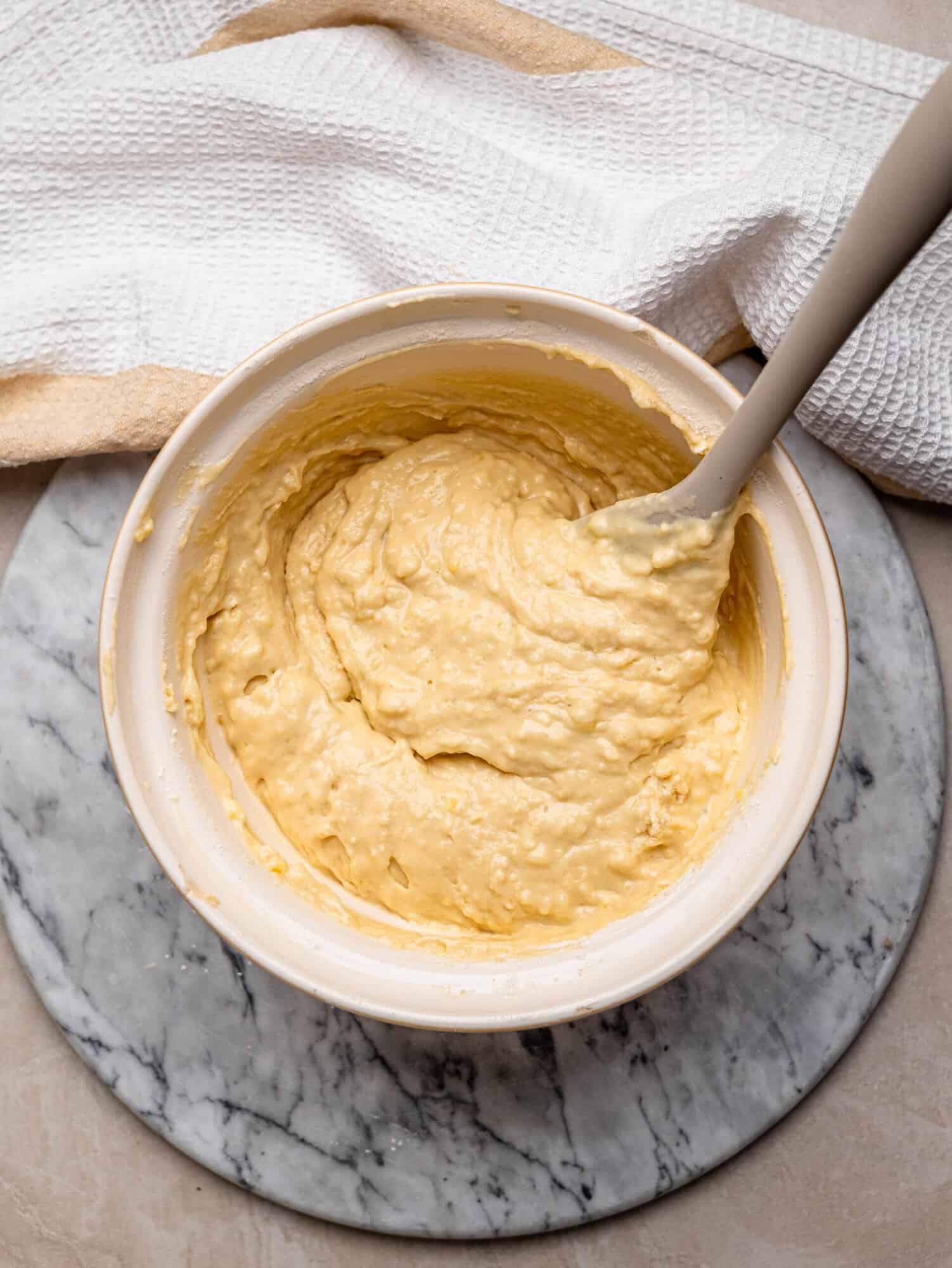 Thick, smooth blueberry muffin batter mixed together in a bowl.