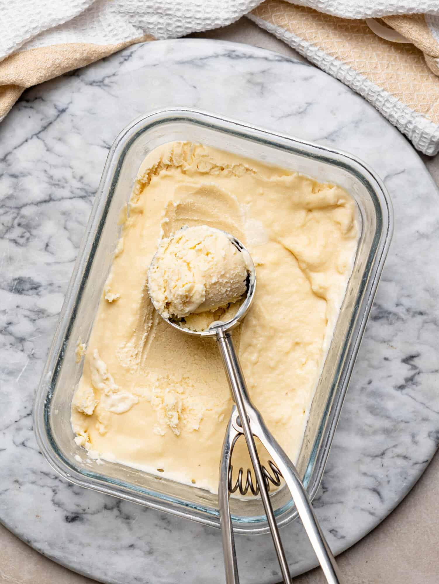 Homemade protein ice cream in a freezer container with an ice cream scoop.