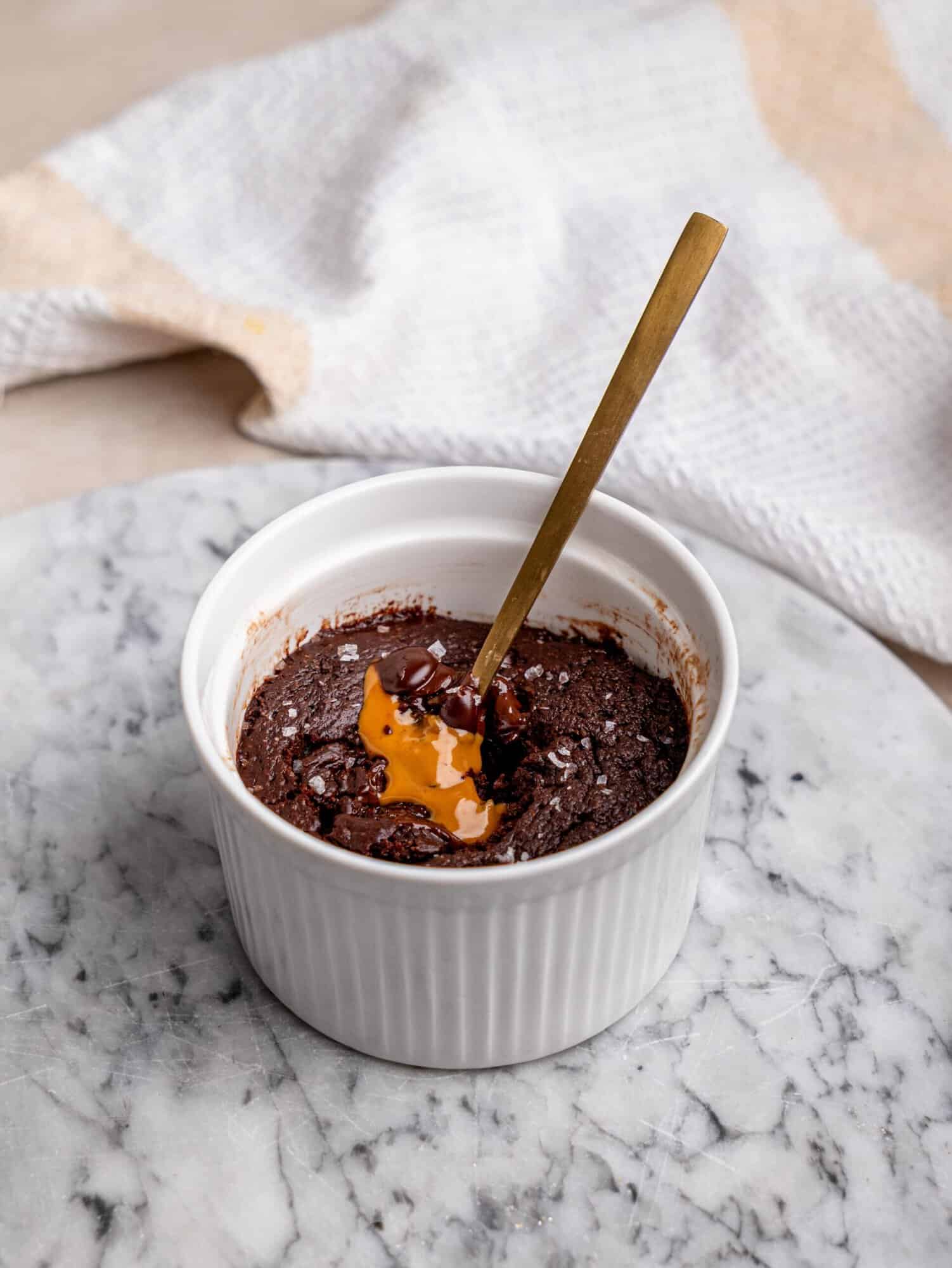 Chocolate protein mug cake filled with melted chocolate and Biscoff spread in a white ramekin.