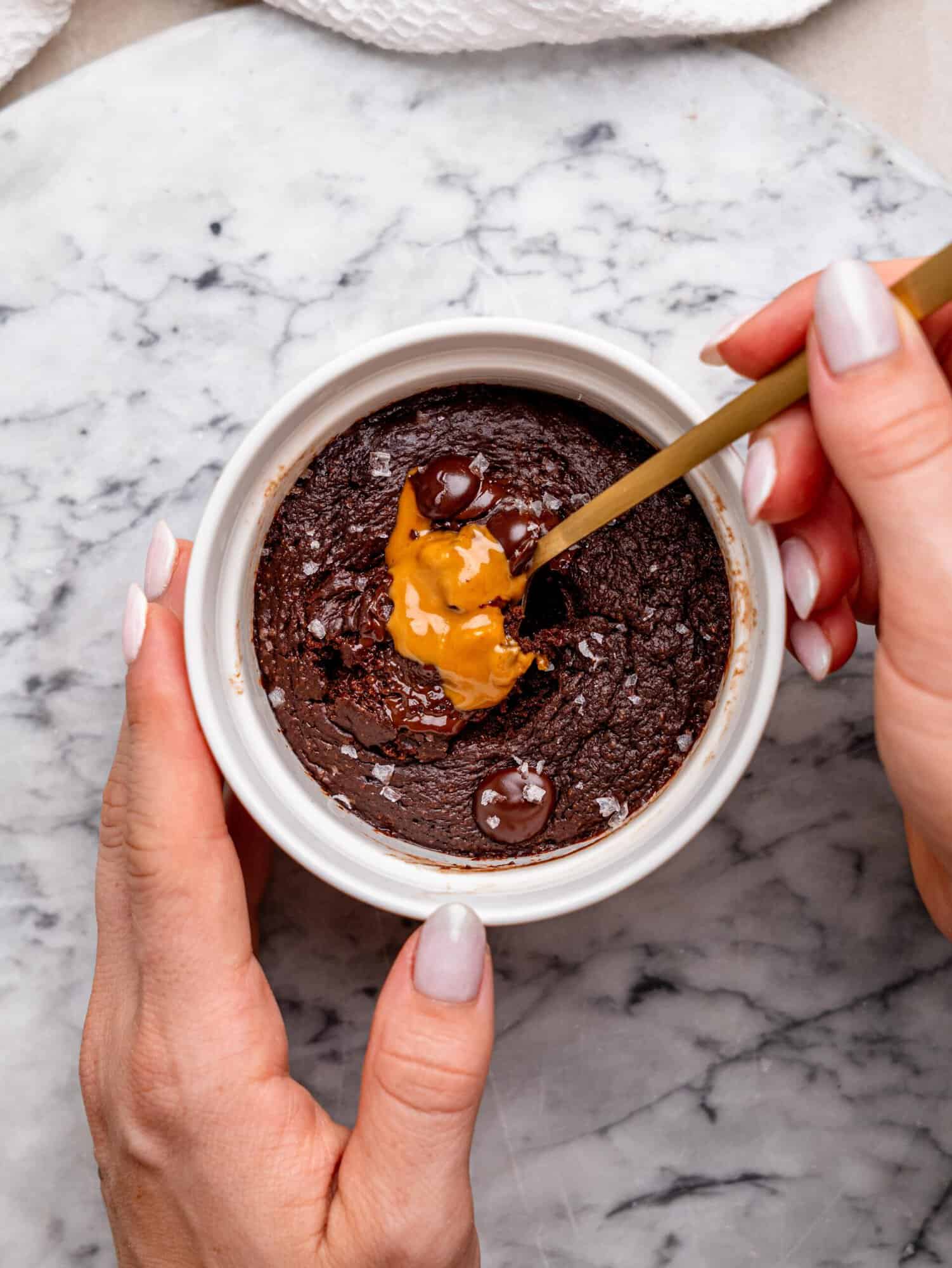 Biscoff chocolate protein mug cake with melted chocolate chips, Biscoff spread, and flaky sea salt, served in a white ramekin.