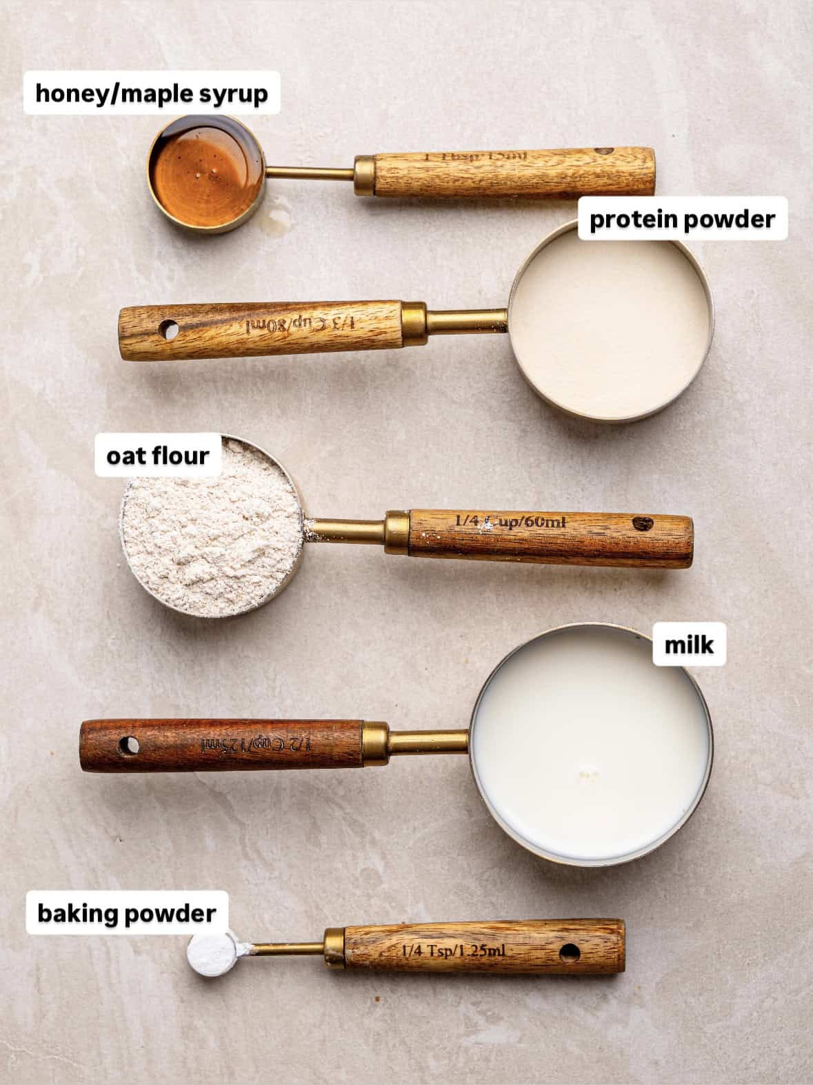 Ingredients for a strawberry white chocolate protein mug cake, including oat flour, protein powder, milk, honey or maple syrup, and baking powder.
