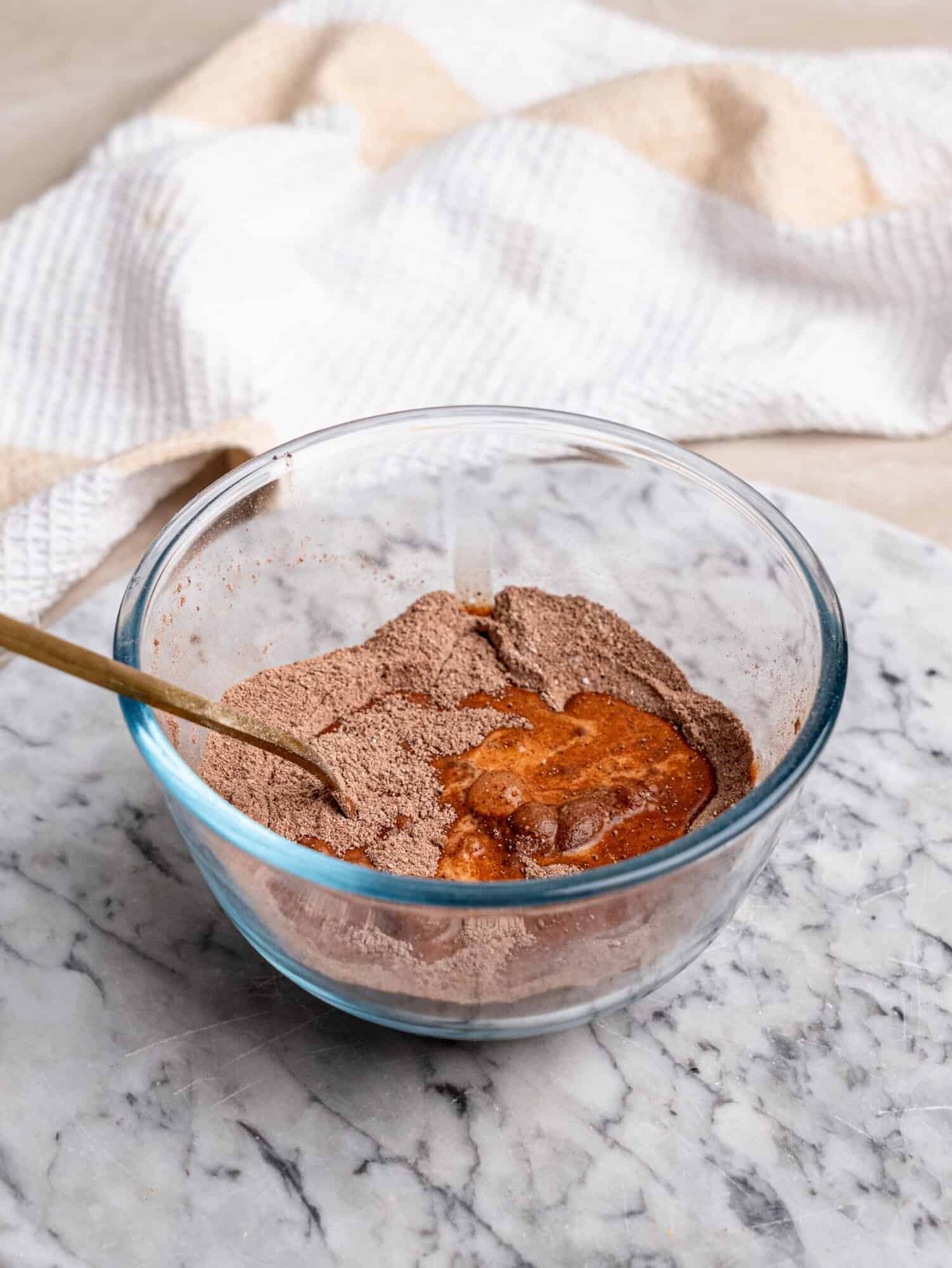 Chocolate protein mug cake batter being mixed in a glass bowl until smooth and thick.