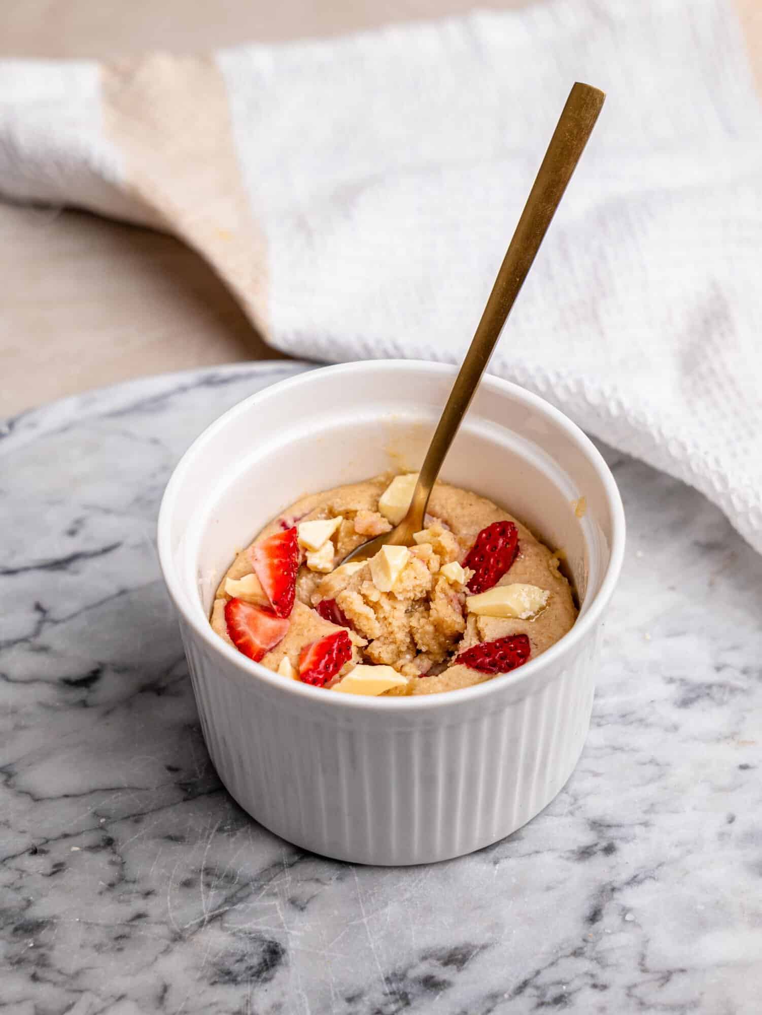 Strawberry white chocolate protein mug cake with fresh strawberries and white chocolate pieces, showing the soft center.