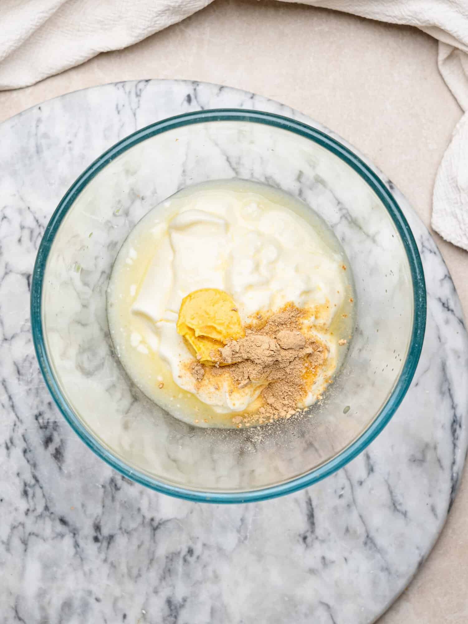 Greek yogurt with lemon juice, Dijon mustard and garlic powder in a glass bowl before mixing into the tuna salad.
